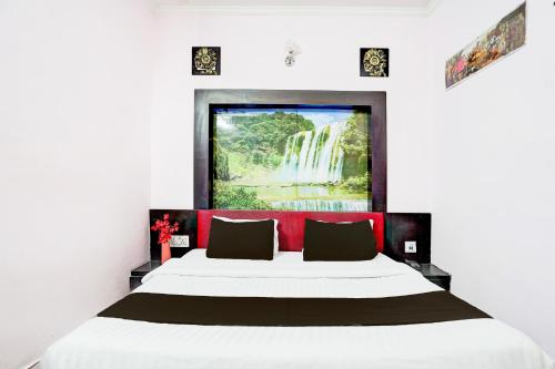a bedroom with a large bed with a waterfall painting on the wall at Super Hotel O Krishna Nagar Chowk Near ONGC in Dehradun