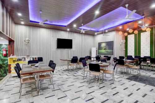 a dining room with tables and chairs and a tv at Super Hotel O Krishna Nagar Chowk Near ONGC in Dehradun