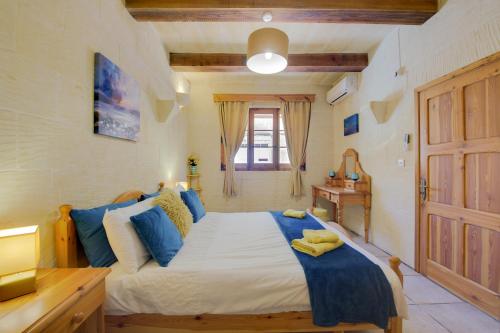 a bedroom with a large bed with blue pillows at Haven Farmhouse with Private Pool and Sea Views in Għajn Melel