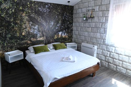 a bedroom with a bed with a tree mural on the wall at Apartmani Drijen in Ravno