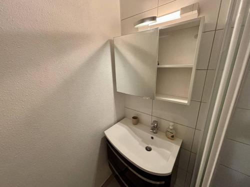 une salle de bain blanche avec un lavabo et un miroir dans l'établissement Appartement climatisé à Argelès-sur-Mer avec Parking - 4 couchages - FR-1-388-52, à Argelès-sur-Mer