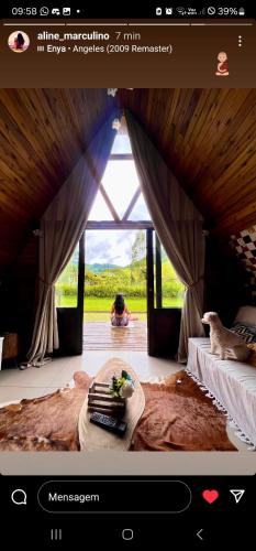 a person sitting in a bedroom with a table in front of a window at Cabana do lago no Sitio Paraiso Joao de Barro in Paraíba do Sul