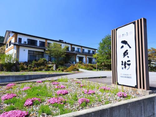 a sign in front of a building with flowers at Oyado Hachibei in Takayama