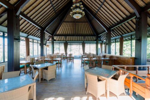 a restaurant with tables and chairs and a chandelier at Mara inn in Nusa Dua