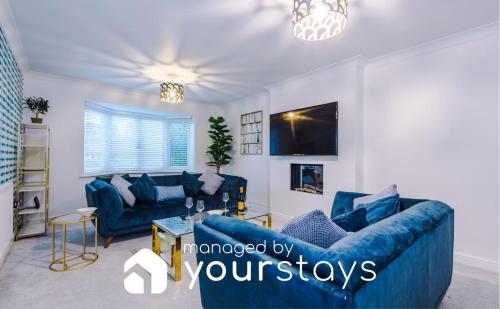 a living room with blue couches and a tv at Kinship House by YourStays - Stunning Holiday Home in the Suburbs in Newcastle under Lyme