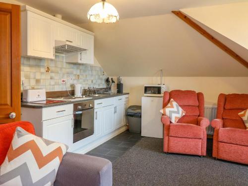 a kitchen with white cabinets and red chairs in a room at Cooinda Flat in Morar