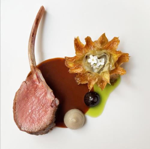 un morceau de viande et une fleur sur une assiette blanche dans l'établissement Hôtel de Tourrel, Saint Rémy de Provence, a Member of Design Hotels, à Saint-Rémy-de-Provence