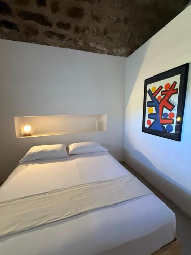 a bedroom with a white bed and a painting on the wall at Al Palazzotto in Pantelleria