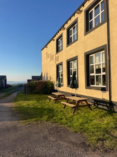 zwei Picknicktische vor einem Gebäude in der Unterkunft Cosy Loft Apartment with Sea Views Above Village Pub The Stag Inn Crosby Maryport in Crosby