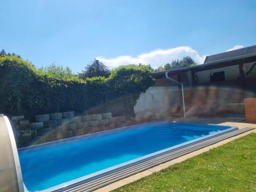 a swimming pool in a yard with a retaining wall at Ferienzimmer Kefeder in Lochenhaus