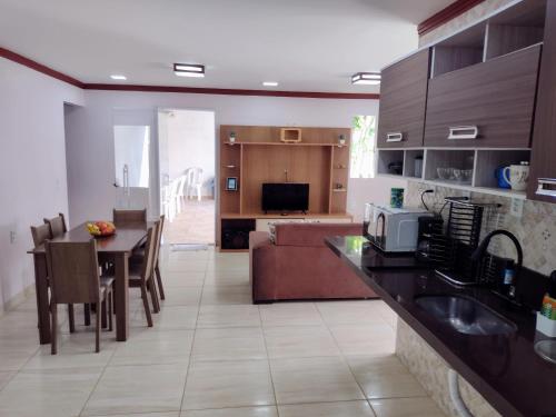 uma cozinha e sala de estar com uma mesa e um sofá em Casa do Sossego na Praia Guarajuba Barra do Jacuipe em Camaçari