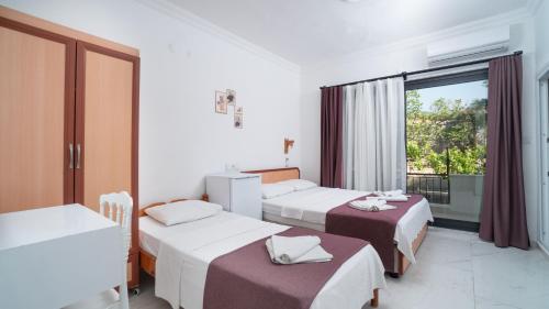a hotel room with three beds and a balcony at Hotel Sema in Patara