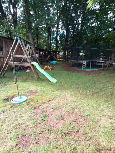 - une aire de jeux avec toboggan dans la pelouse dans l'établissement Séjour à la ferme, à Valuéjols