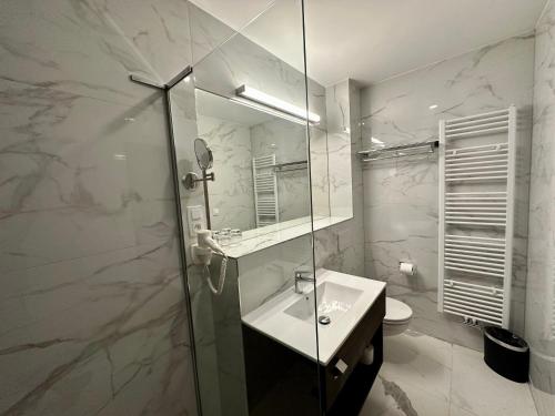 a white bathroom with a sink and a mirror at Pension Village in Karlovy Vary