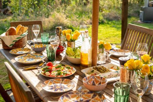 a wooden table with plates of food and wine glasses at Luxury Glamping The Wye Valley for 2 to 4 Guests in Ross on Wye