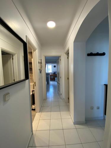 a hallway with white walls and a white tile floor at Apartamento na Praia in Vieira de Leiria