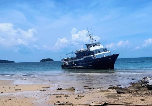 a large boat in the water next to a beach at Ripples Guesthouse and Sky Bar in Koh Rong Sanloem