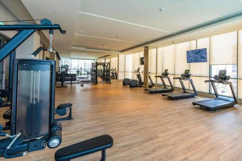 a gym with a bunch of treadmills and machines at SettlerHomes - 2BR Downtown Haven, Ideal For Family Comfort in Dubai