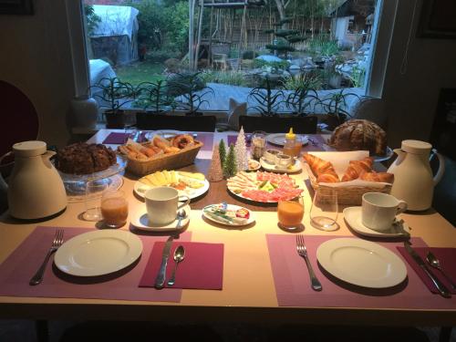 a table with plates of food on a table with a table cloth at Le Jardin De La Tuilerie Alsace in Pfastatt