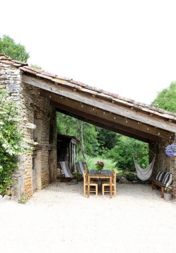 un patio avec une table et des chaises sous un bâtiment en pierre dans l'établissement VESTIGES, ancien corps de ferme rénové selon l'esprit wabi-sabi, à Saint-Antonin