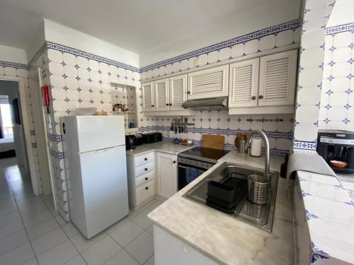 a kitchen with white cabinets and a white refrigerator at Apartamento na Praia in Vieira de Leiria
