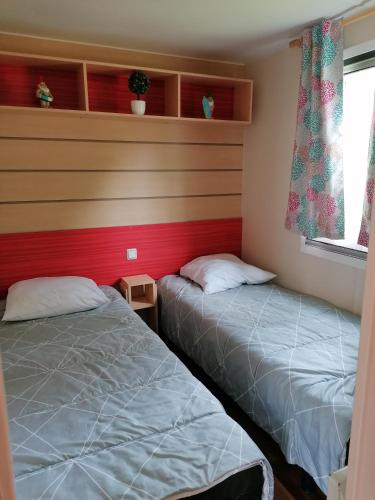 une chambre avec deux lits et un mur rouge dans l'établissement Mobile home camping du lac de Bairon, à Le Chesne