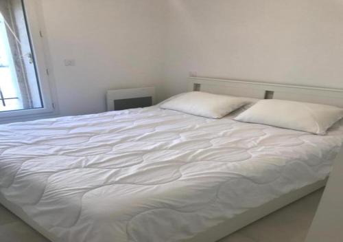 un lit blanc avec deux oreillers dessus dans l'établissement Appartement Port-Vendres Rénové, à Port-Vendres