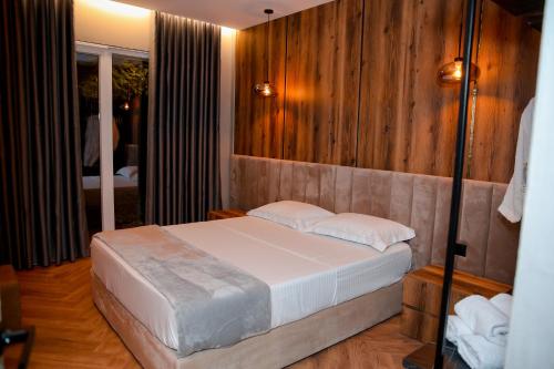 a bedroom with a bed with wooden walls and a mirror at N'Gen Luxury Villas - Razem in Razëm