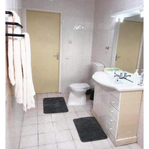 a white bathroom with a sink and a toilet at Paramaribo Villa Near Vibrant District incl Kitchen Household Service in Paramaribo