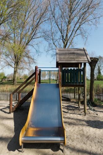 a slide in a playground with a wooden structure at Appartement de Schaapskooi in Heinkensand