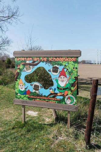 a sign sitting in the grass next to a fence at Appartement de Schaapskooi in Heinkensand