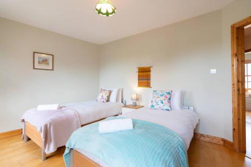 two beds in a room with white walls at Central Stay - Old Town Dingle in Dingle