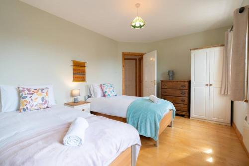 a bedroom with two beds and a dresser at Central Stay - Old Town Dingle in Dingle