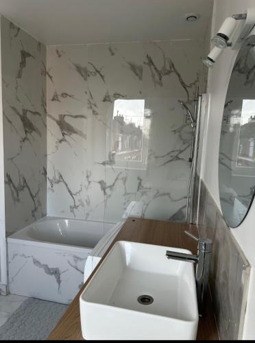La salle de bains blanche est pourvue d'un lavabo et d'une baignoire. dans l'établissement Sweet mother share studio, à Lille