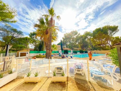 une piscine de complexe avec un palmier et des gens dans l'eau dans l'établissement Spacieux T3 dans une résidence avec piscine, à Sanary-sur-Mer