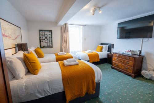 a hotel room with two beds and a television at Without A Paddle Hotel in Llangollen