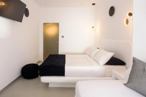 a white bedroom with a bed and a couch at Tataki Family Hotel in Fira