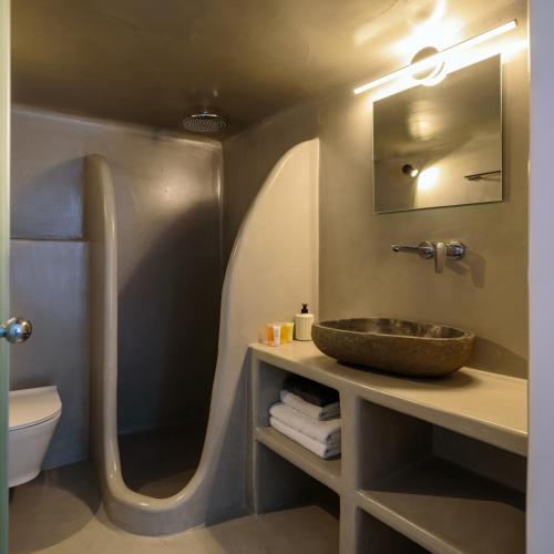 a bathroom with a sink and a toilet and a mirror at Tataki Family Hotel in Fira