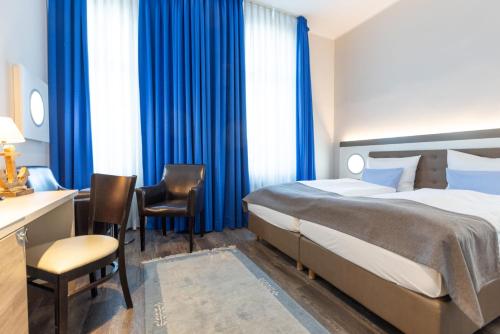 a hotel room with a bed and a desk and chairs at Best Western Plus Theodor Storm Hotel in Husum
