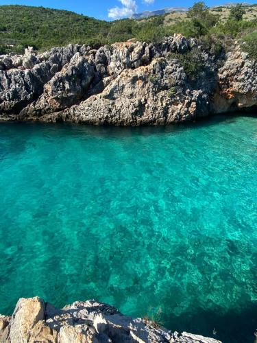 a body of water next to a rocky shore at Hummingbird in Qeparo