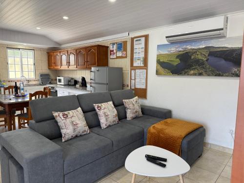 a living room with a couch and a kitchen at Casa dos Morros in Lajes das Flores