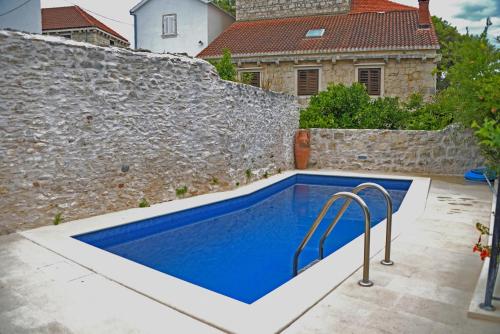 a swimming pool in front of a stone wall at Apartments Villa Nada in Sutivan