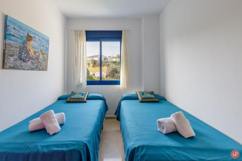 two twin beds in a room with a window at Views of the Blue in Torrox