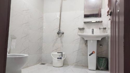 a white bathroom with a toilet and a sink at Aangan Residences in Skardu