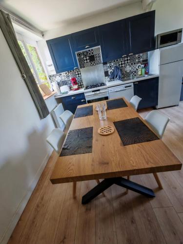 une table en bois dans une cuisine avec des armoires bleues dans l'établissement Gîte Nature sur LAC avec accès PISCINE et PONTON, à Éguzon-Chantôme