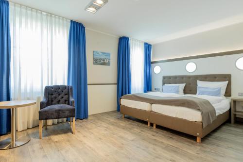 a bedroom with a bed and a chair and a table at Best Western Plus Theodor Storm Hotel in Husum