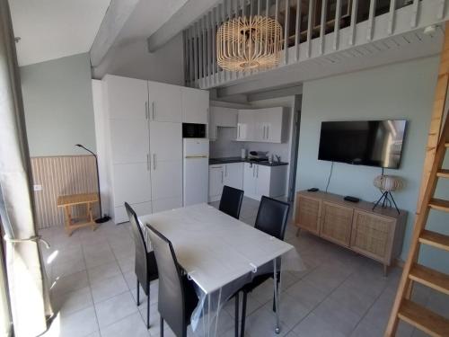 une cuisine et une salle à manger avec une table et des chaises dans l'établissement Appartement en bord d'étang, au Barcarès