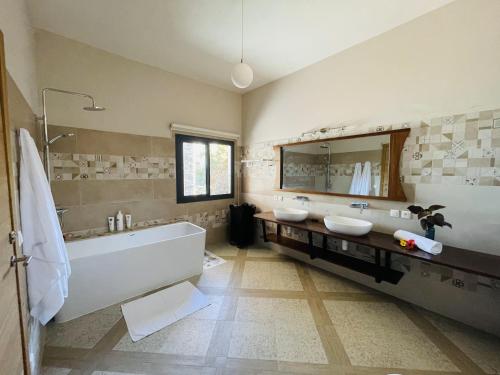 a bathroom with two sinks and a tub and a mirror at LA MAISON RIVARIA L'expérience d'une villa entière rien que pour vous in Sainte Marie