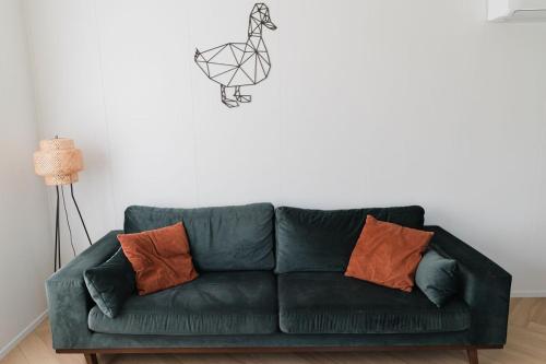 a green couch with orange pillows in a living room at De Eend - Tiny house in de Zeeuwse Natuur in Driewegen