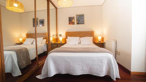 a bedroom with two beds and a mirror at Pensión O Camiño in Sarria